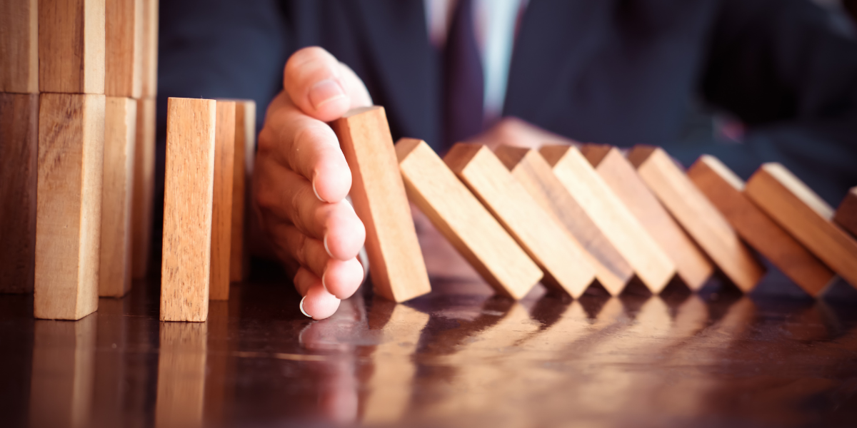 Man stacking wood blocks to assess grant management risk in uncertain times