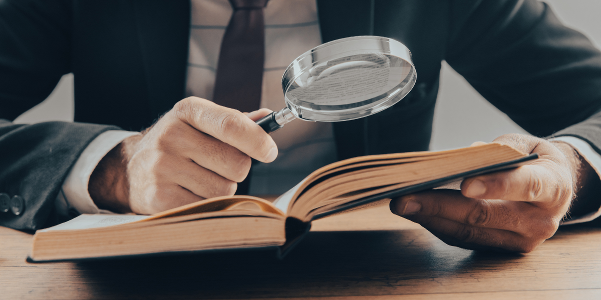Grant Manager holding a magnifying and a book searching for grant management myths