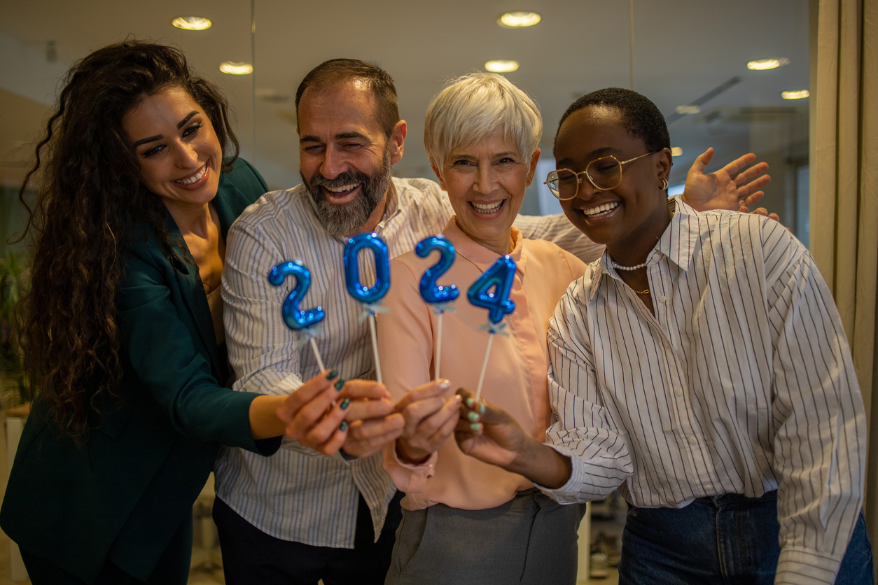 Four grant managers holding up balloons for each number of 2024 in their office.